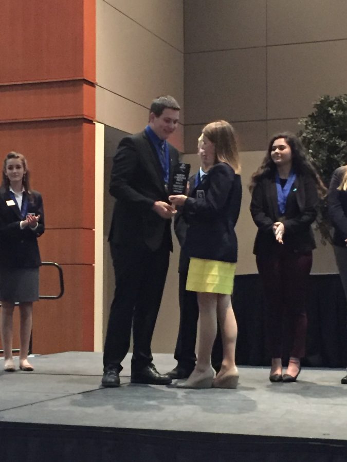Standing on stage, Thomas Armstrong receives a trophy for a principles of marketing event. DECA is a very beneficial program at Millbrook and will be going to Greensboro for states in March.