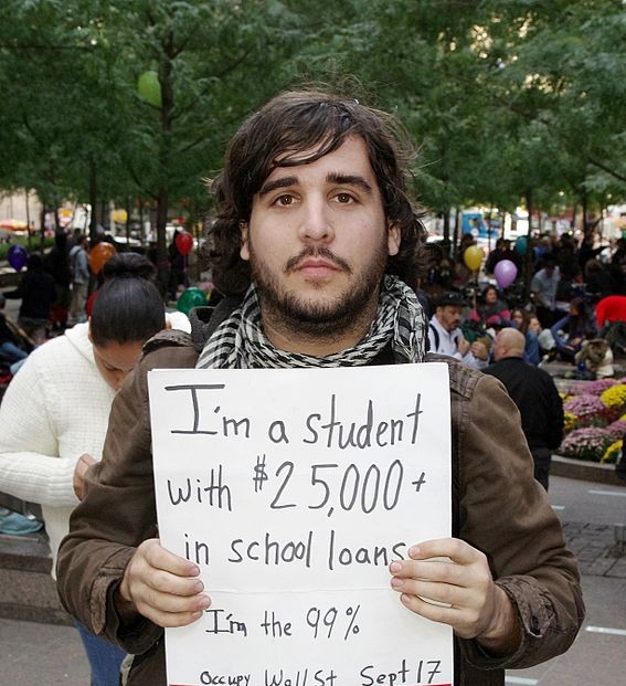 Protesting at an occupy Wall Street March, this man holds up a sign presenting his astronomical student loan debt. He is just one of millions.
