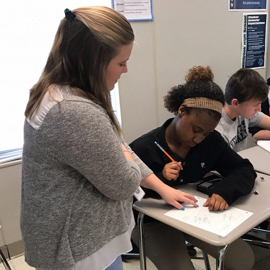 Walking around the classroom, Ms. Conrad helps her student, Justice Hoskins, with one of her math problems. Ms. Conrad works hard to ensure that all of her students understand the material and know how it would be used in everyday life.
