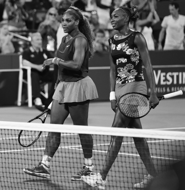 Discussing a point during a doubles match, Venus(left) and Serena(right) are playing in their first round match of the US Open. This family tandem has won more than any other in the history of womens tennis. 
