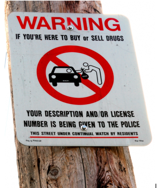 One+of+many+examples+of+the+criminalization+of+drug+use%2C+this+sign+prohibits+the+exchange+of+drugs.+However%2C+many+are+proposing+a+new+approach+in+which+there+are+safe+sites+for+addicts+to+take+their+drug+with+clean+needles+and+information+about+rehabilitation.