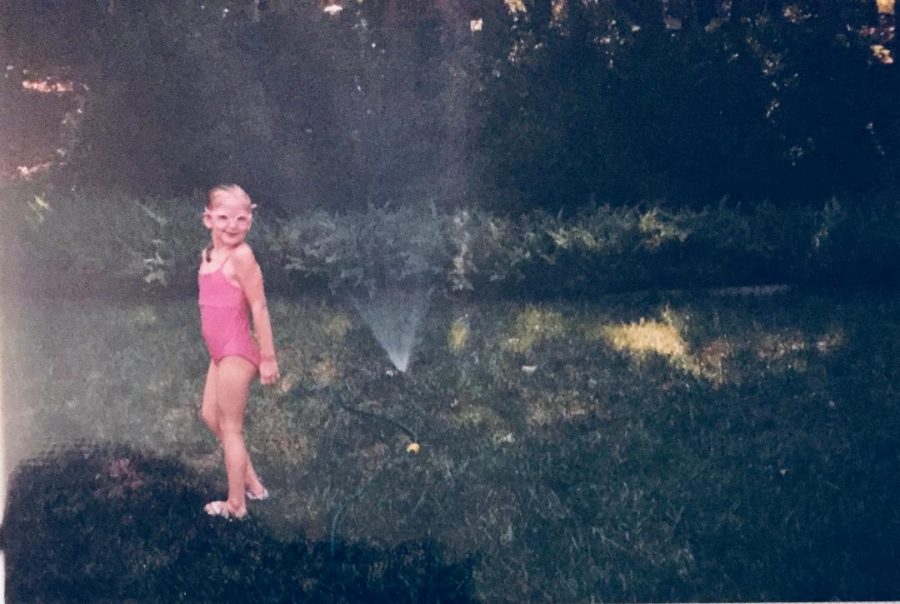 Frolicking in the sprinkler, a young Margaux Hunter wears her goggles like sunglasses. The best way to beat the heat is to mess around in the sprinkler, because no one will judge you, for they are too busy being jealous. 