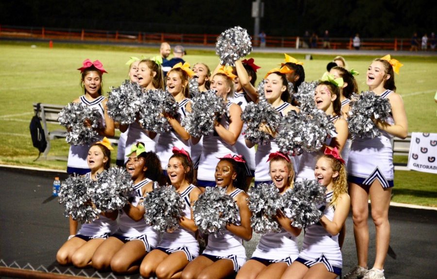 Showcasing their energy and spirit, these cheerleaders are getting the crowd excited for a football game. They lead cheers not only for the team to take part in, but also for the crowd to shout aloud in unison.
