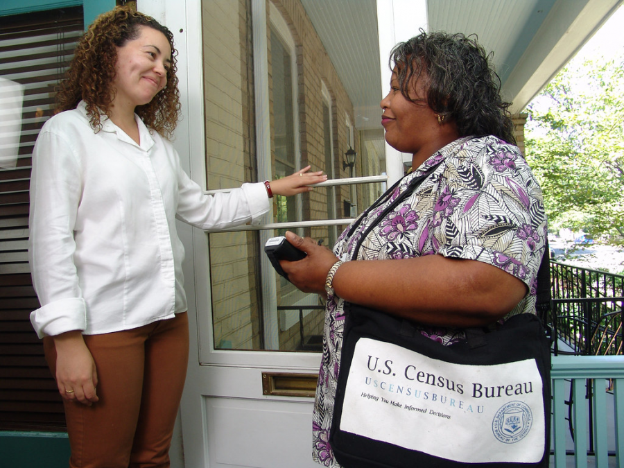 Taking responses from a woman on her front porch, this Census worker is tasked with getting accurate data about population size and demographics within each household. The survey is used to allocate electoral votes and funding for goods in public use, such as healthcare, education and public transportation.