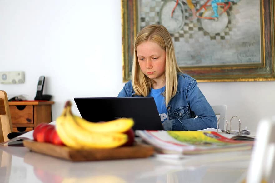 Focusing on the screen, a student engages with school activities from the comfort of her home. Learning virtually from home can be challenging when it feels like you are constantly connected, so taking breaks is important for eye and overall health.