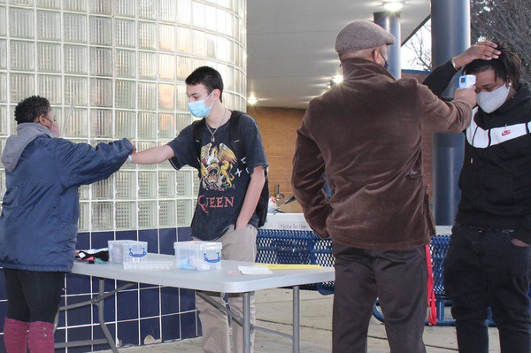 Standing six-feet apart, checking temperatures, and putting on wristbands, Mr. Dowden and Ms. Clarke helps students re-enter the building after one year of online learning. Students learn the new rules and regulations as starting a new and very unfamiliar journey, and begin adjusting to the new normal.