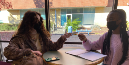 Ashley Synder is giving her pencil to Kendall Johnson while they both work in the library. This is one of the many ways Ashley shows kindness to her peers.