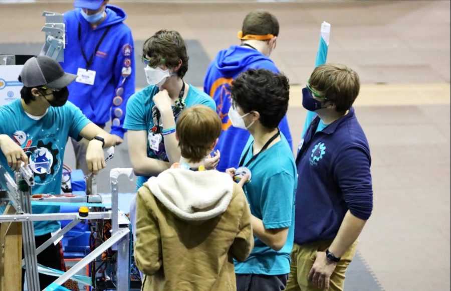 Preparing for their next match, the Millbrook GearCats Drive Team huddles around George the Robot to discuss game strategy. The Drive Team consists of a coach, two drivers, one human player, and a technician.