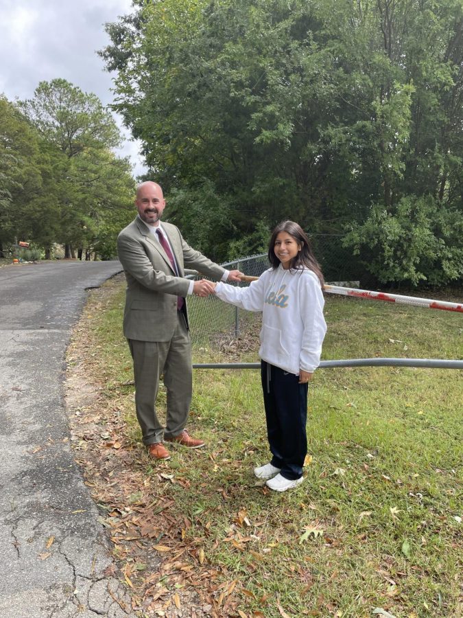 Shaking hands in front of the Johnsdale gate Dr. Saunders and Aracely Gomez smiling. The is now open and should truly help student life. 