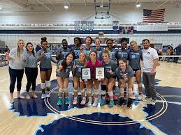 The Womens Millbrook Volleyball team celebrating their victory over the Heritage Huskies and showing off their conference championship plaques.