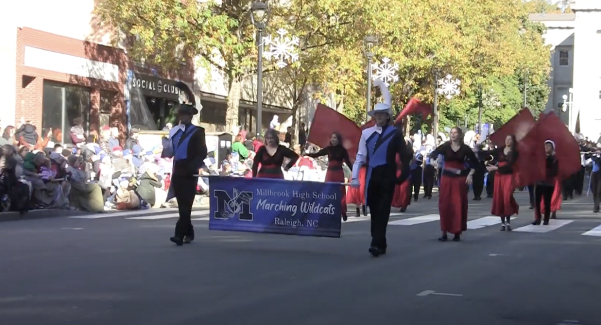 Photo of the Millbrook High School Color Guard performing in front of the marching band, David Uy.