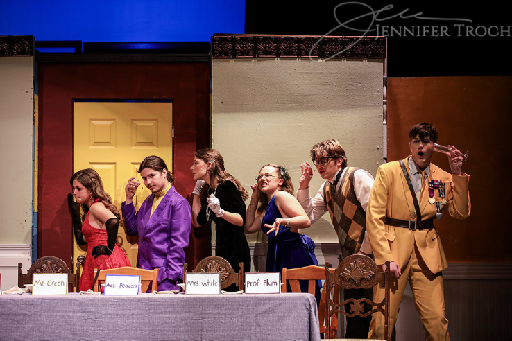 From left to right: Mrs. Scarlet (Berklee Axford), Professor Plum (Tristan Gonzalez), Mrs. White (Lily Greenberg), Mrs. Peacock (Dotty Faircloth), Mr. Green (Kael Alley), and Colonel Mustard (Noah Wilson).